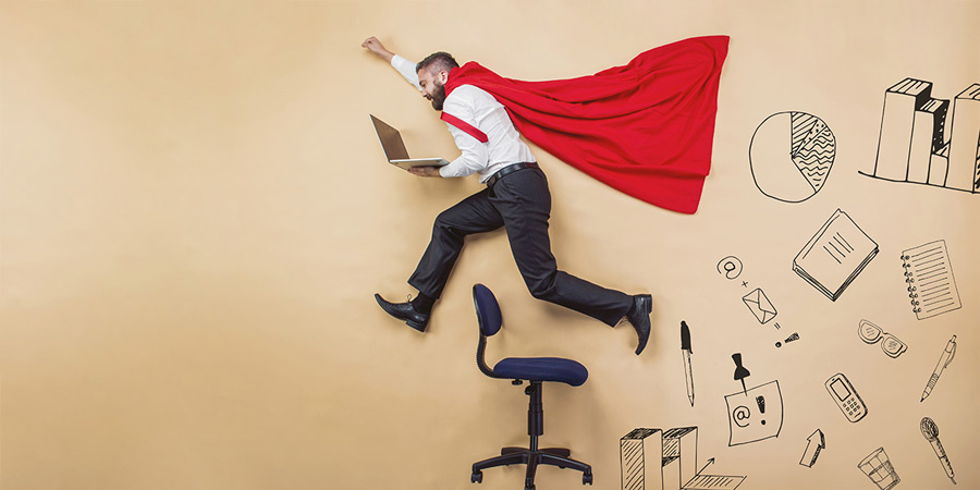 Image of a man wearing a red cape jumping over a computer chair while holding a laptop